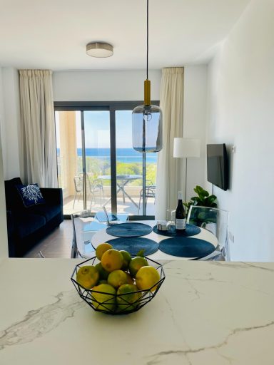 View from the open kitchen through the bright, modern living and dining room, out over the balcony to the sea.